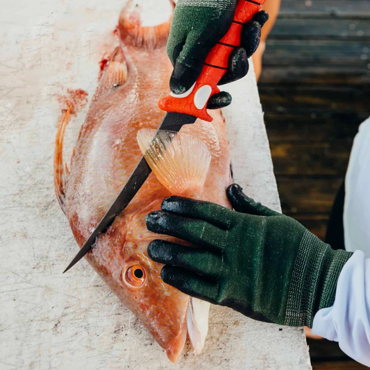 Person filleting a fish with a knife on a cutting board