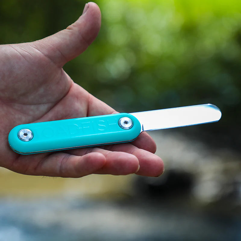 Turquoise pocket knife held in a hand with a natural background