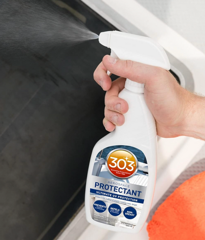 Person using a 303 Aerospace Protectant spray bottle on a car window.