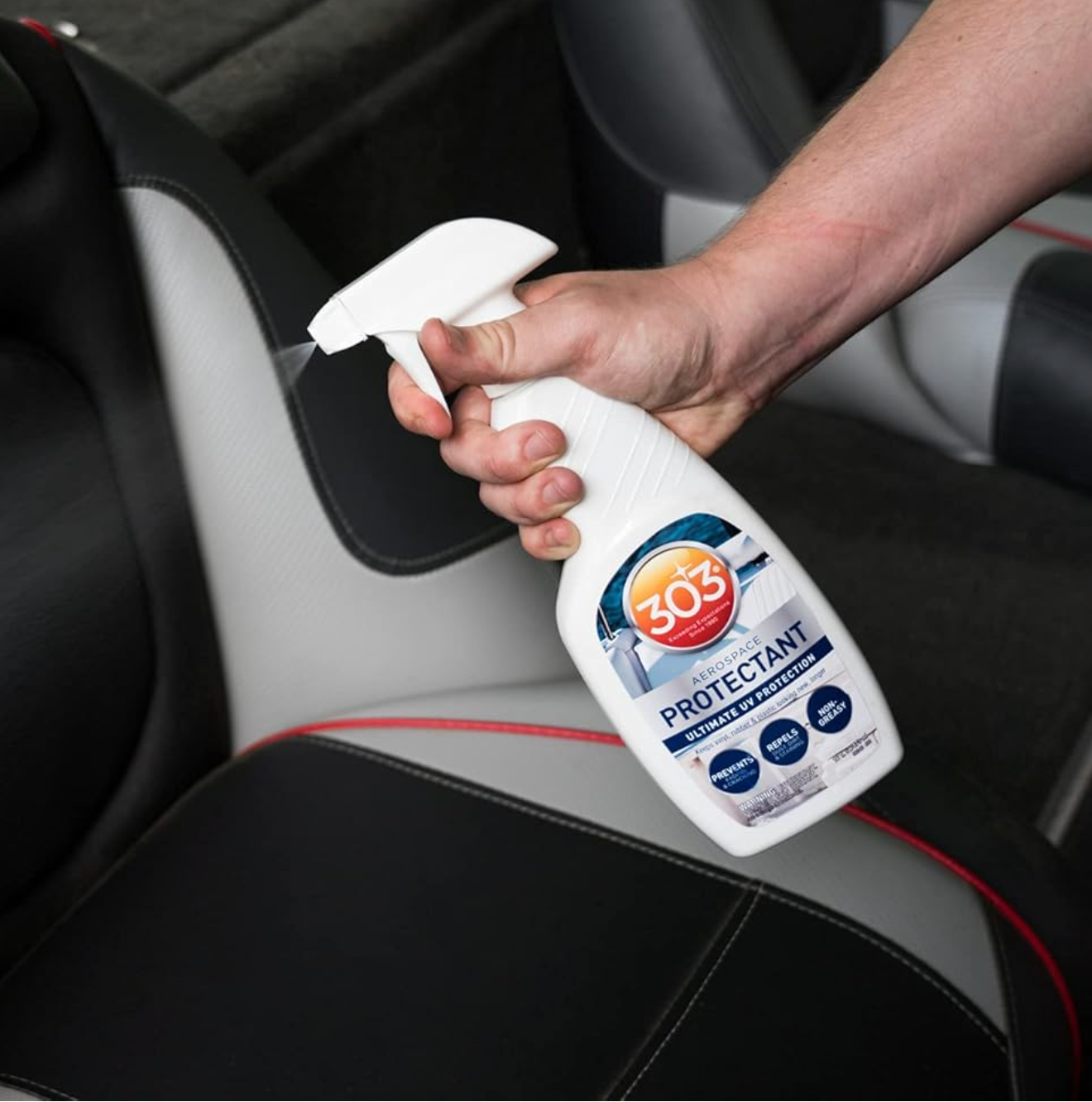 Person holding a bottle of 303 Protectant over a car seat