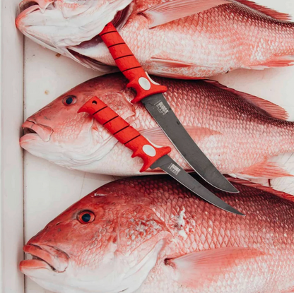 Red fish with a sharp knife on a white surface