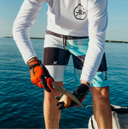Person holding a knife with water and a boat in the background