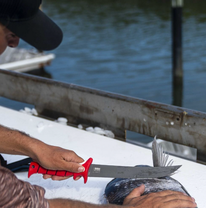 Person holding a knife to cut a fish on a boat with water in the background