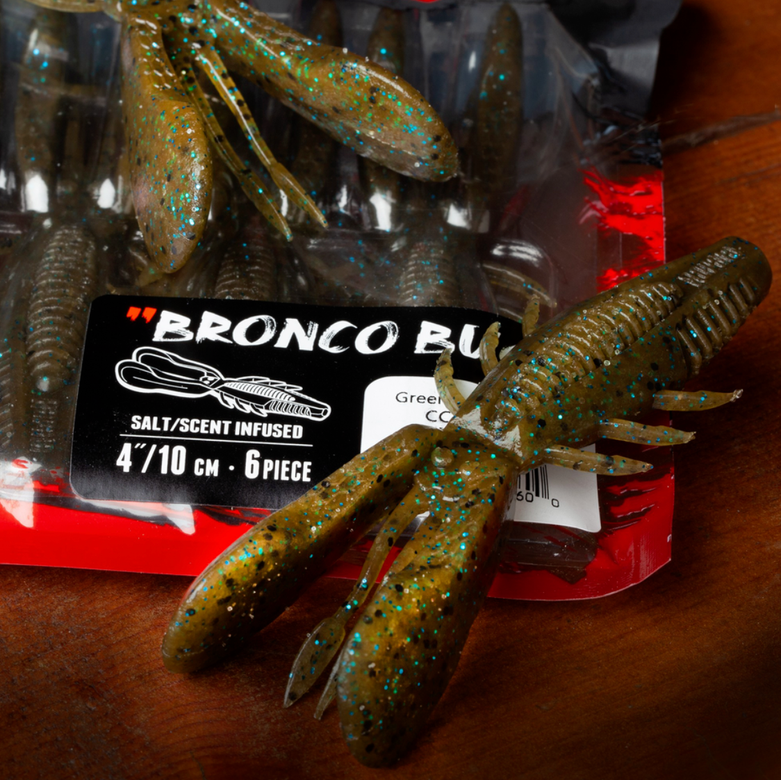 Fishing lures with 'Bronco Bait' packaging on a wooden surface