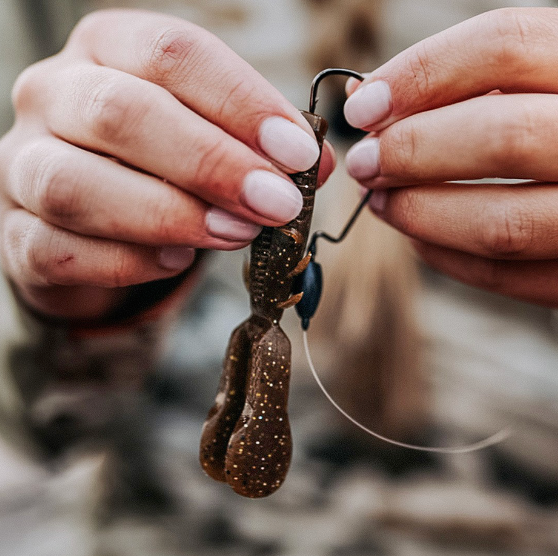 Close-up of hands holding a fishing lure with a blurred natural background