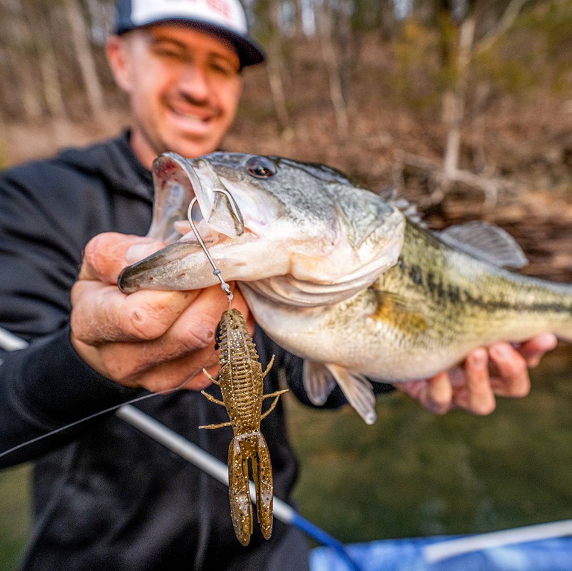 Man holding a largemouth bass caught on a lure with a blurred natural background