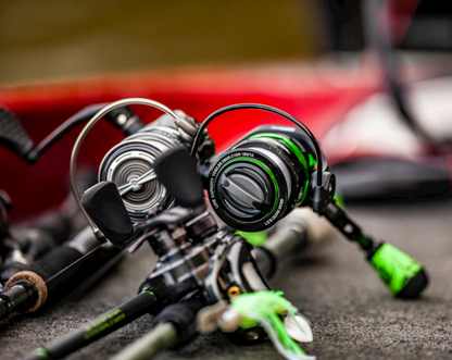 Green and black fishing reel on a white background
