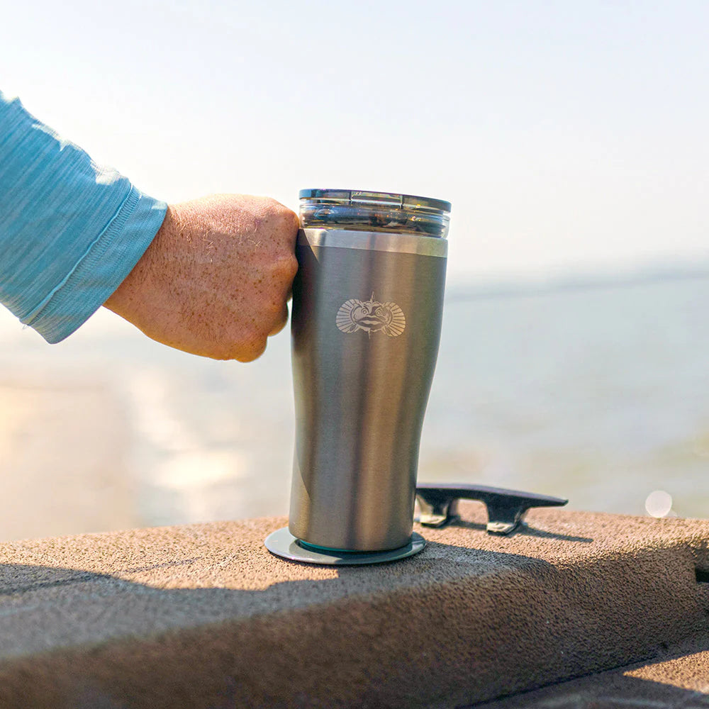 Person holding a stainless steel tumbler with a logo against a blurred natural background