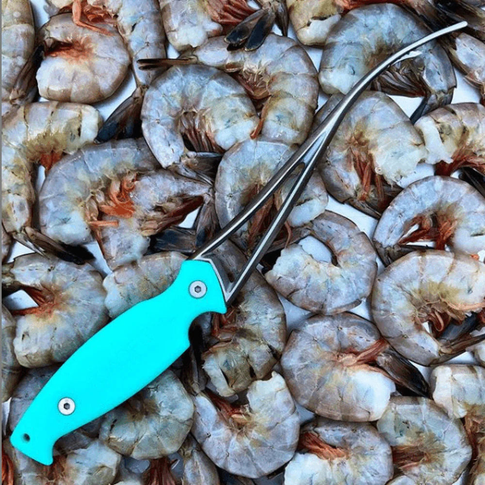 Teal kitchen shears on a pile of raw shrimp