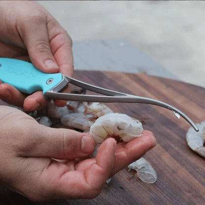 Person using kitchen shears to devein shrimp on a wooden cutting board.