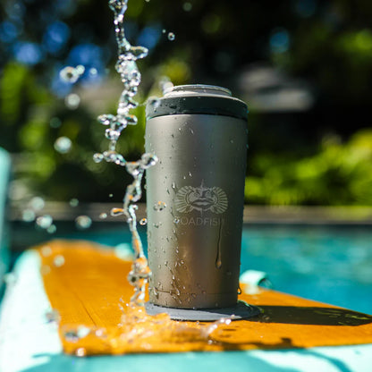 Gray tumbler with a brand logo being splashed by water on a yellow surfboard by a pool.