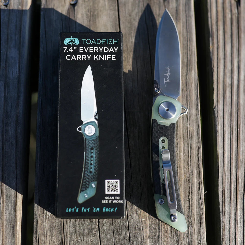 Folding knife with Toadfish packaging on a wooden surface