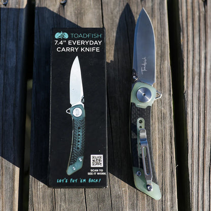Folding knife with Toadfish packaging on a wooden surface