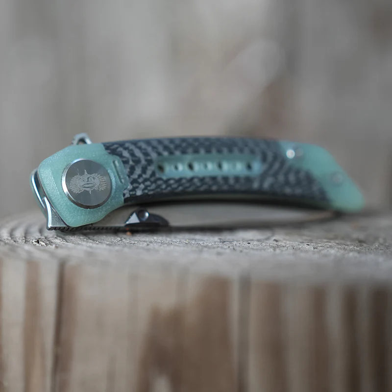 Teal and black folding knife on a wooden surface with a blurred background
