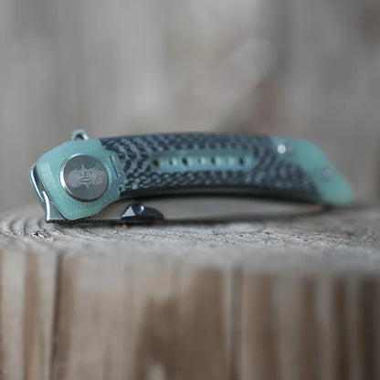 Teal and black folding knife on a wooden surface with a blurred background