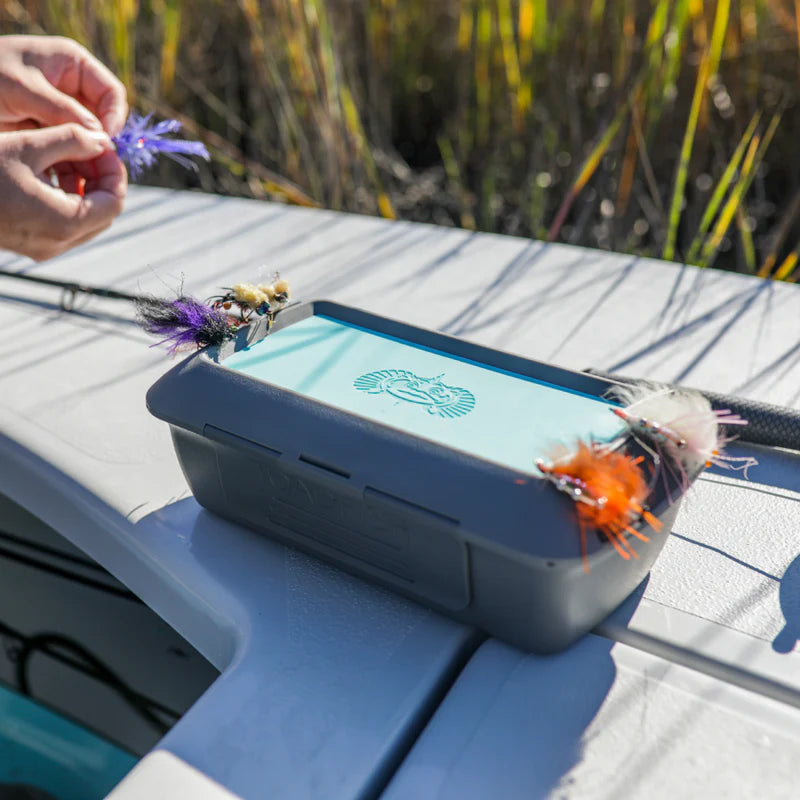 Fishing fly box with flies on a table outdoors