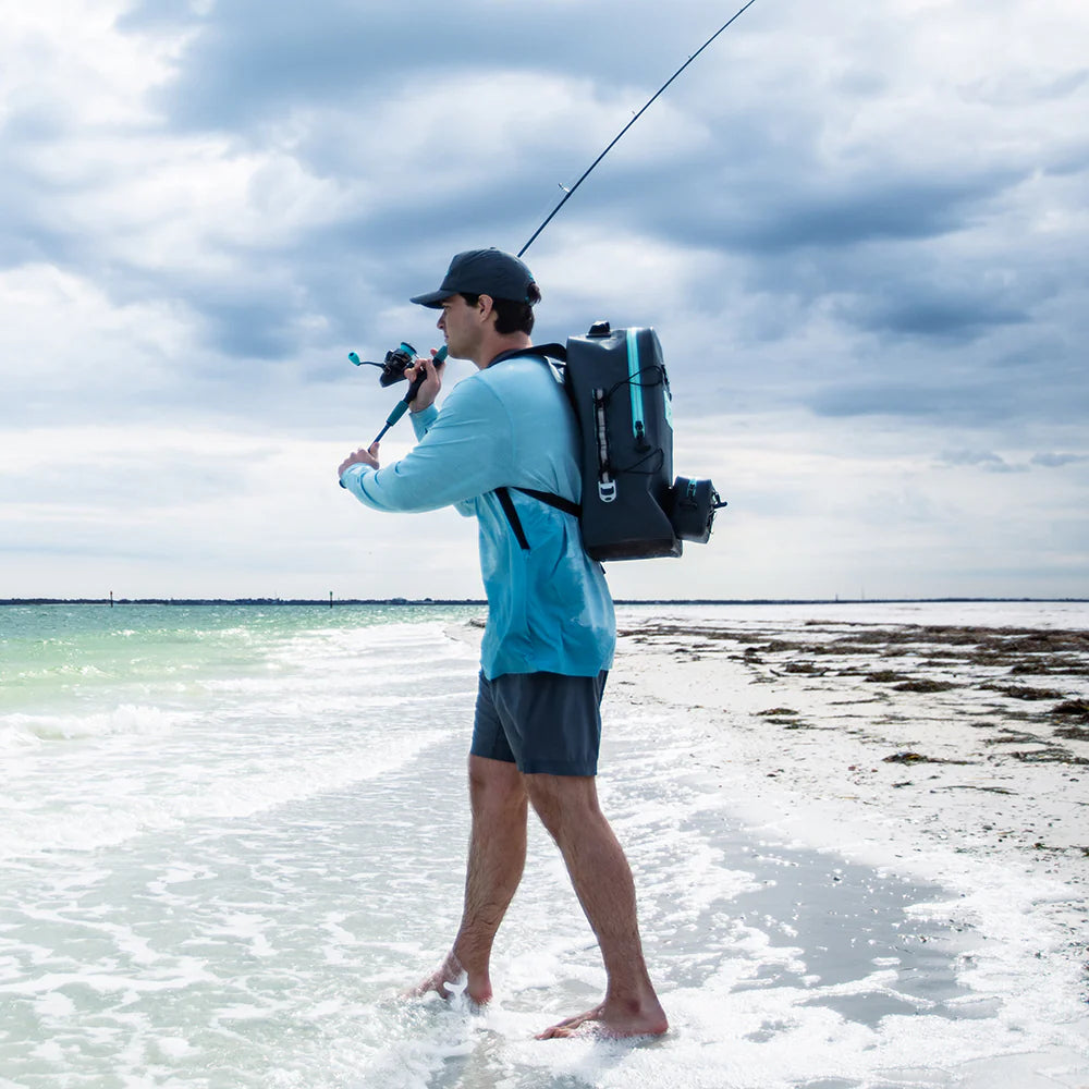Man with a fishing rod and backpack standing on a beach