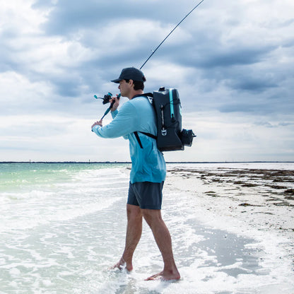Man with a fishing rod and backpack standing on a beach
