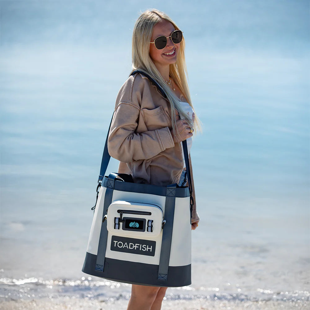 Woman holding a TOADFISH cooler bag on a beach