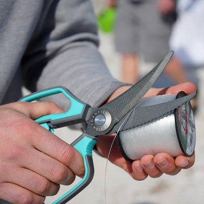 Person holding a fishing line spool and scissors with a blurred background